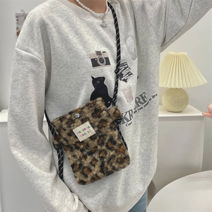 Close-up of plush leopard print crossbody bag with woven strap and snap button closure