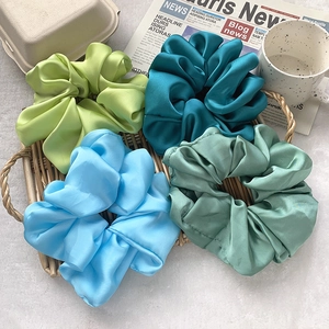 Set of four oversized satin scrunchies in Morandi blue and green tones on a tray