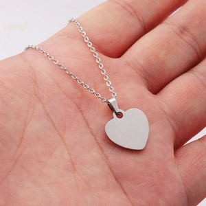 Close-up of a silver polished heart pendant necklace held in hand to show size and shine