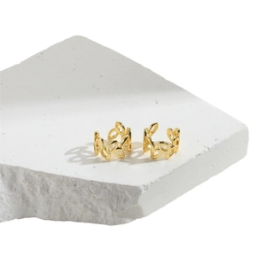 Minimalist 14K gold plated leaf cuff earrings displayed on a white textured stone