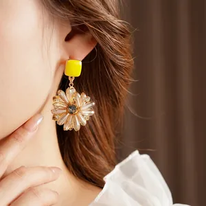 Elegant yellow enamel flower drop earrings with clear crystal petals on a model