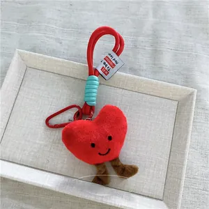 Dettaglio di portachiavi a cuore di peluche rosso con moschettone e viso ricamato