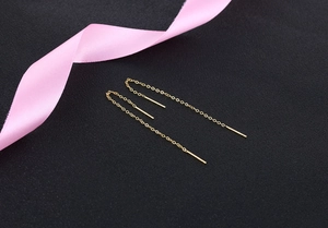 Detailed macro view of minimalist long gold chain tassel earrings on black texture