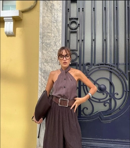 Detail of knot-neck halter top paired with pleated wide-leg trousers and a leather belt