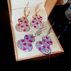 Macro shot of gold and silver gourd-shaped earrings with red and pink zircons