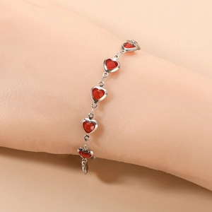 Vue détaillée d'un bracelet à maillons argentés avec six pendentifs cœur en verre rouge