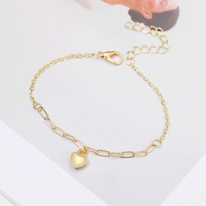 Detailed view of a gold heart pendant bracelet with a polished finish and adjustable chain