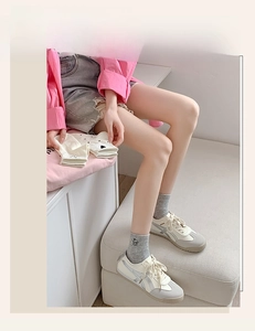 Close-up of white socks with black heart embroidery paired with retro beige sneakers