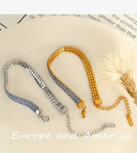 Détail du fermoir mousqueton et du tag gravé K18 sur les bracelets de luxe dorés
