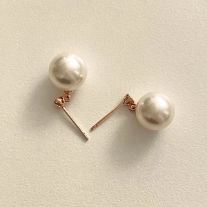 Detailed close-up of cream white pearl earrings with elegant rose gold metal base