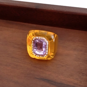 Macro detail of vintage amber resin ring with a rectangular purple crystal centerpiece