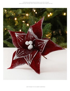 Deep red flocked Christmas flower decoration with white berries and bokeh background