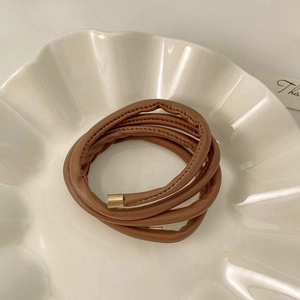 Close-up of a brown faux leather spiral hair tie with elegant gold metal end caps