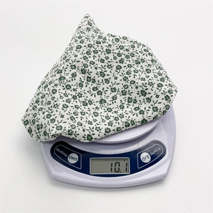 Detailed view of lightweight 10.1g chiffon fabric with floral daisy pattern on a scale