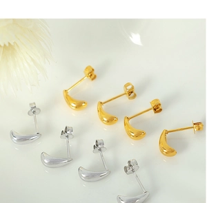 Close-up of minimalist teardrop stud earrings in polished gold and silver finishes