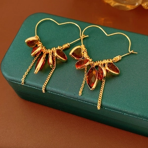 Detail of 18K gold plated heart hoop earrings with red marquise gems and chain tassels