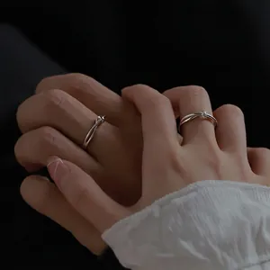 Silver Mobius knot couple rings with small diamonds worn on hands in a romantic setting