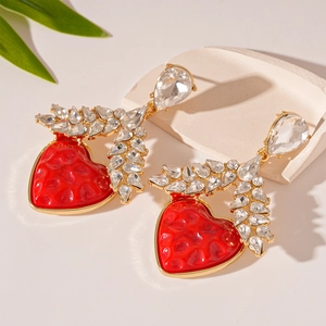 Close-up of red heart earrings with golden wheat ear pattern and sparkling rhinestones