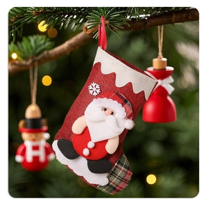 Detail of burlap Christmas stocking with 3D Santa doll hanging on pine branch
