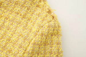 Close-up of yellow and beige tweed fabric with subtle glitter fibers for women jacket