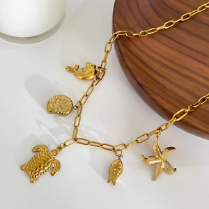 Collier doré 18K avec pendentifs étoile de mer et tortue sur plateau en bois