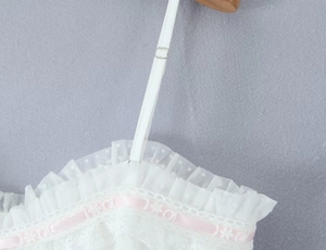Detail eines weißen Netz-Tops mit rosa Blumenstickerei und verstellbaren Trägern