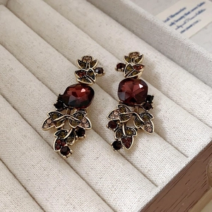 Detail of vintage bronze earrings with burgundy gemstones and colored rhinestones in box