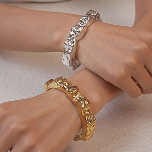 Detailed view of irregular liquid metal texture bangles in gold and silver finish