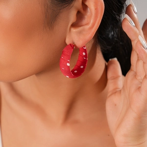 Detailed view of model wearing a red polka dot fabric hoop earring in a New Chinese style