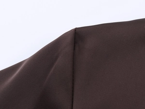 Détail de chemise en satin marron foncé montrant les coutures sur tissu tissé