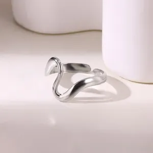 Polished silver wave ring on minimalist pedestal with smooth fluid lines