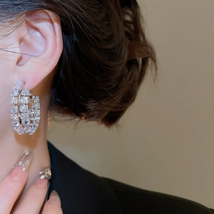 Gros plan de boucles d'oreilles créoles argentées géométriques avec zircons sur le modèle