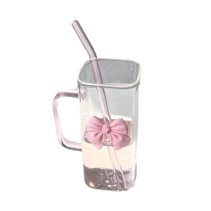 Square glass tumbler with pink bow decor and straw on a clean white background
