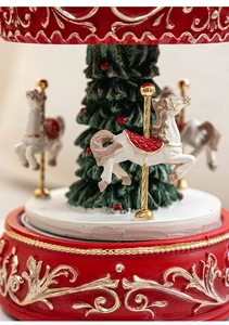 Close-up of resin Christmas carousel music box with golden floral patterns and tree