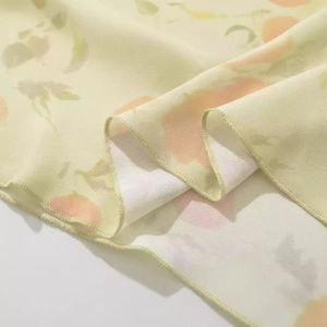 Vue macro du tissu en mousseline jaune pâle avec imprimé pêche et détails d'ourlet cousu