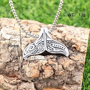 Polished silver whale tail pendant showing dimensions 42mm by 29mm on a natural bark