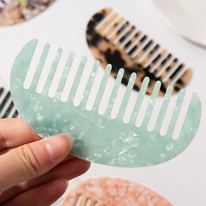 Light green acetate hair comb with marble texture in a minimalist crescent shape