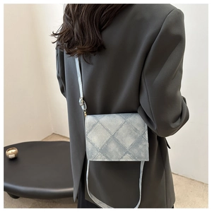 Detail of light blue quilted denim crossbody bag with adjustable strap on model