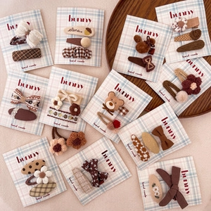 Flat lay detail of kids fabric strawberry hair ties and bear clips in warm earth tones