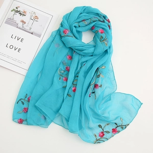 Close-up of pink flower embroidery on a light blue chiffon scarf with leaf details