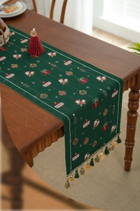 Detailed view of dark green Christmas table runner with festive jacquard and gold tassels