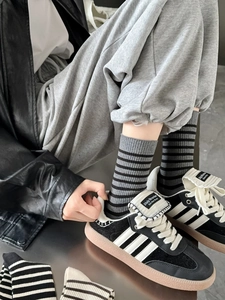 Detail of gray and black striped crew socks worn with retro sneakers and casual pants