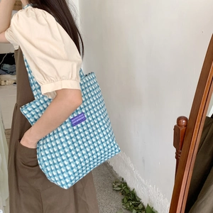 Blue and white checkered wool tote bag with a purple woven label shown on a model