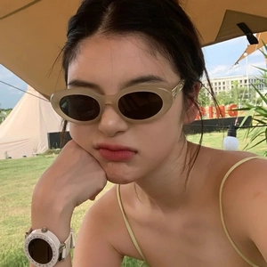 Retro oval beige sunglasses with brown lenses shown on a model in outdoor setting