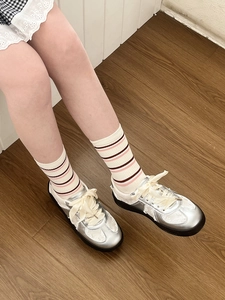 Close-up of striped cotton socks paired with silver metallic sneakers and satin laces