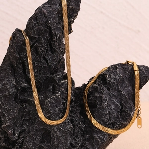 Detailed view of 18K gold plated herringbone snake chain set on volcanic rock background