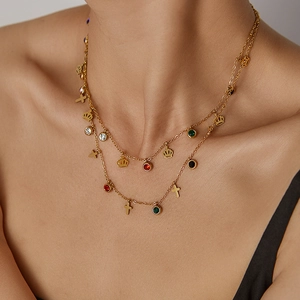 Detail of double-layered gold necklace with colored zircon charms and crown pendant