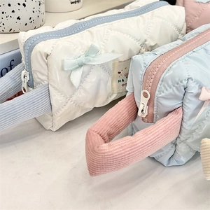 Detailed view of quilted bow makeup bags in white and light blue glossy fabric
