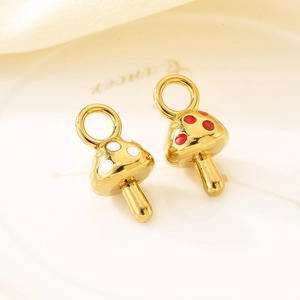 Detailed macro view of two gold stainless steel mushroom charms with red and white enamel