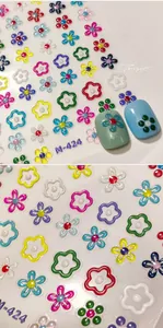 Macro detail of 3D floral nail art stickers with embossed texture and gold accents